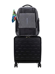 A gray and black backpack stacked on top of a black rolling suitcase against a plain white background, with a small South African flag hanging from the side of the backpack.