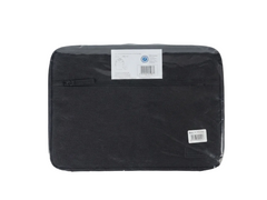 A black fabric tablet sleeve or laptop pouch, still sealed in its clear plastic retail packaging, with two white labels attached. The sleeve is photographed flat against a plain white background.