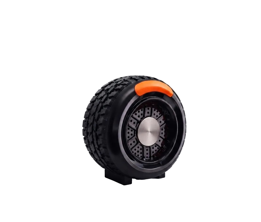 A rugged black tire-style wheel speaker with a metallic silver center and a bright orange accent ring, displayed on a clean white background.